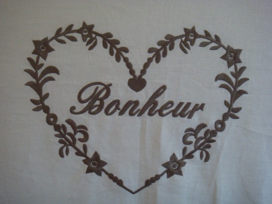 Détail de la tête de lit brodée « Bonheur »