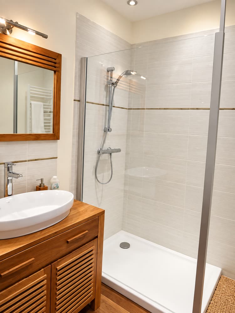 La salle de bain de la chambre Bonheur, douche à l'italienne et vasque posée sur un meuble de bois
