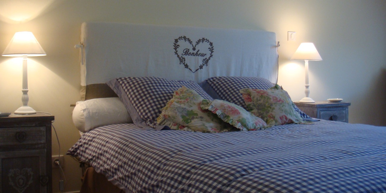 Le lit de la chambre Bonheur, tête de lit brodée d'un cœur