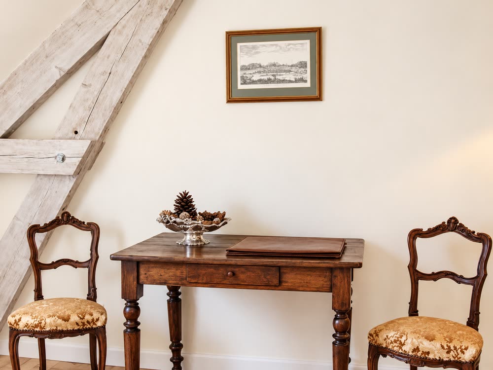 Le coin bureau de la chambre Fontainebleau, table de bois et chaises anciennes sous la charpente