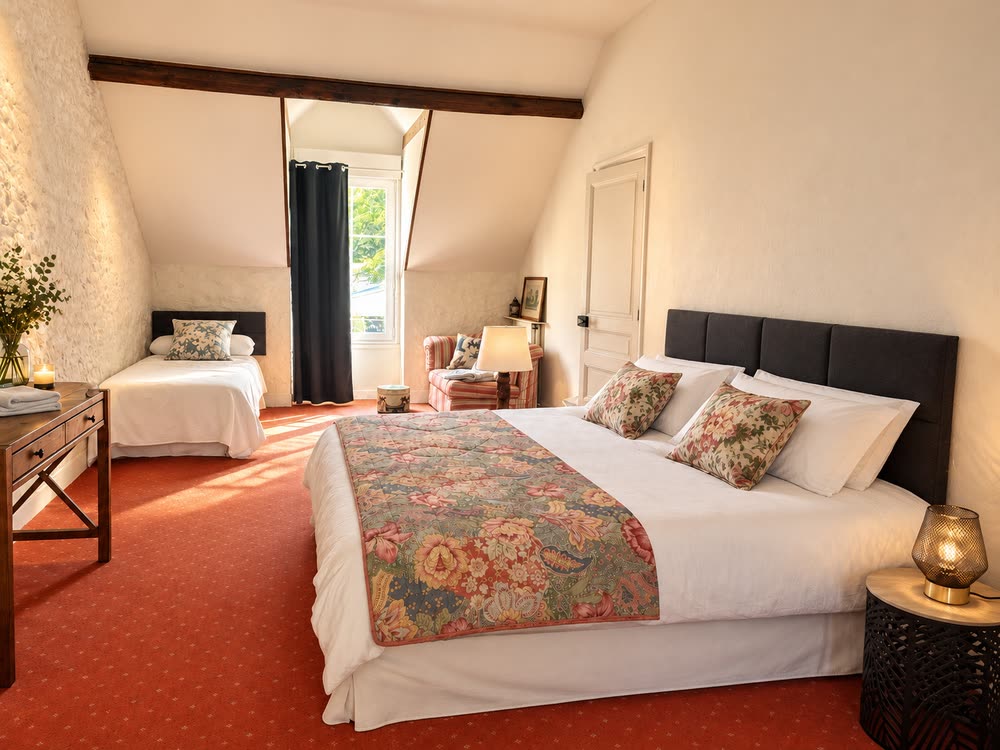 Une chambre familiale du gîte, un lit double et un lit simple sous les poutres apparentes