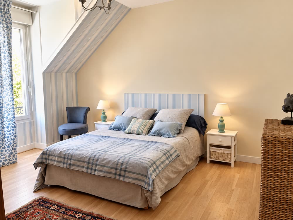 Une seconde chambre du gîte, tête de lit claire et fauteuil près de la fenêtre